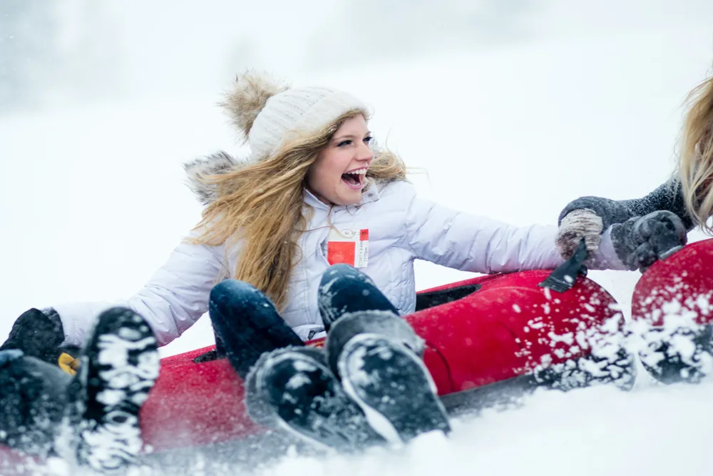 woman having a great time tubing down snowy hill