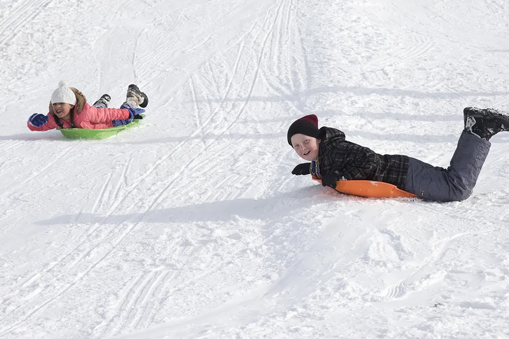 two kids happily snowtubing