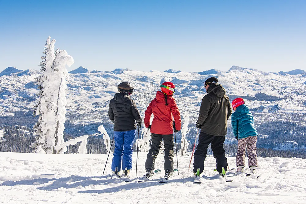 four skiers standing on top of mountain