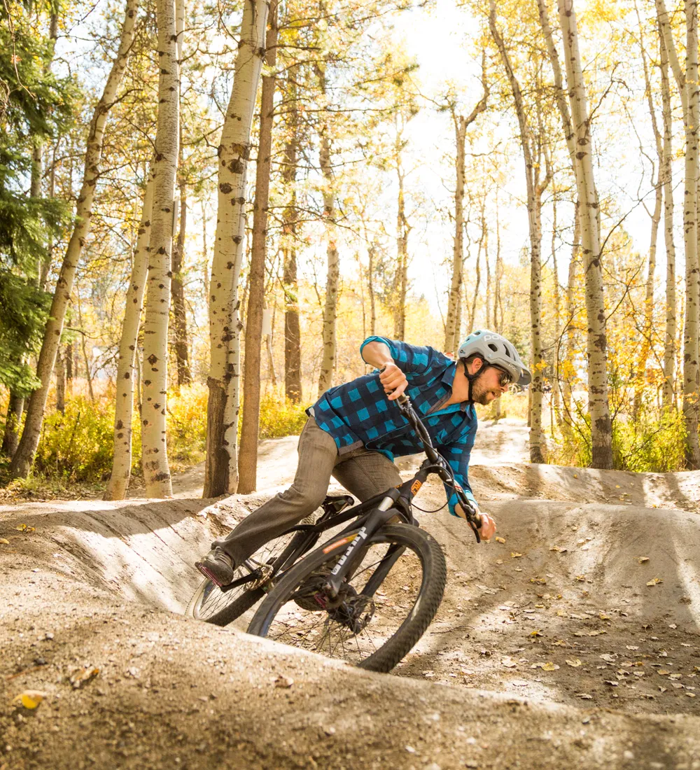 man in flannel mountain biking on pump track