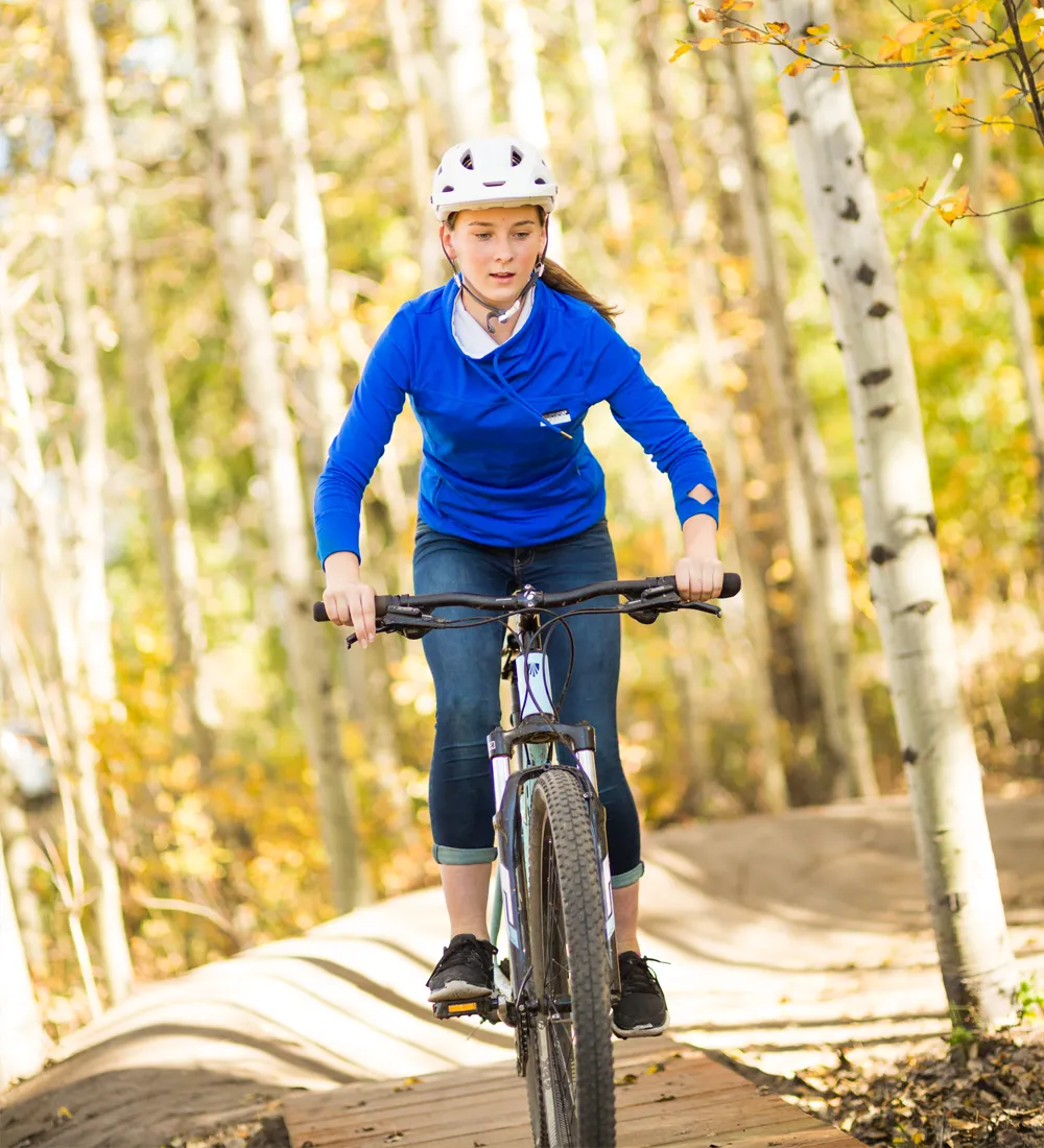 teen in blue shirt mountain biking on pump track