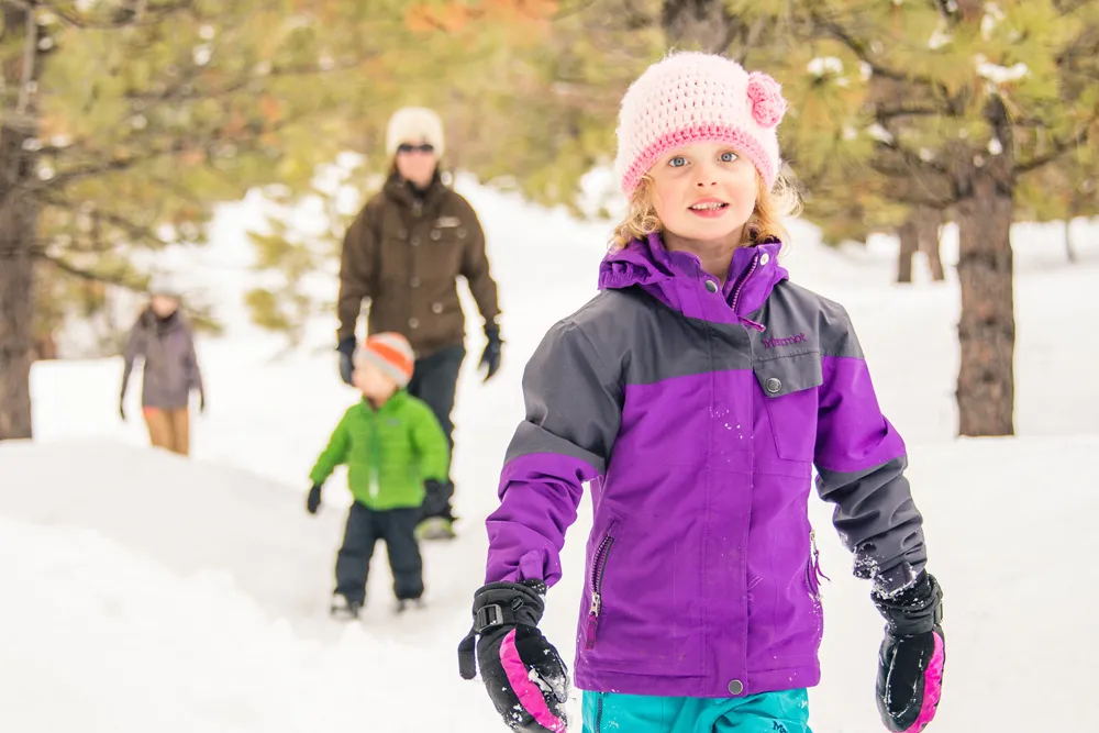 young girl snowshoeing with her family